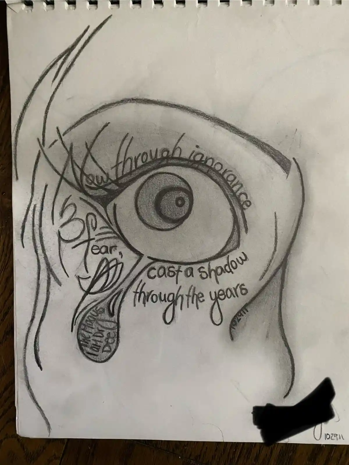 A hand-drawn pencil sketch on spiral notebook paper shows a large, detailed eye with a tear falling from it. The tear is…