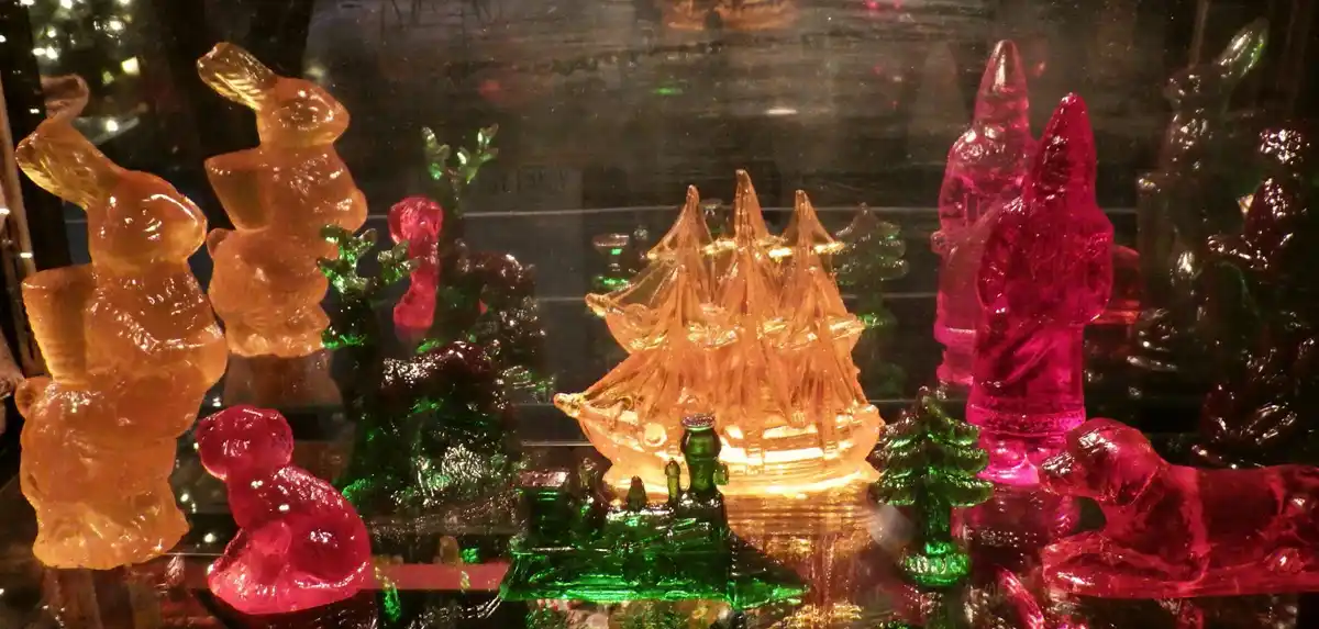 A display of colorful, translucent plastic figurines including bunnies, a ship, trees, and animals, arranged in a glass case…