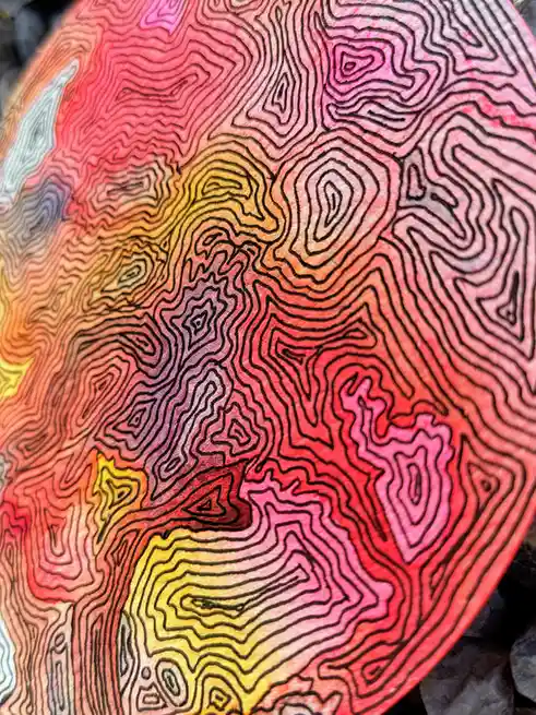 A close-up of a colorful, hand-drawn topographic map with wavy contour lines in a rainbow gradient from yellow to red to…