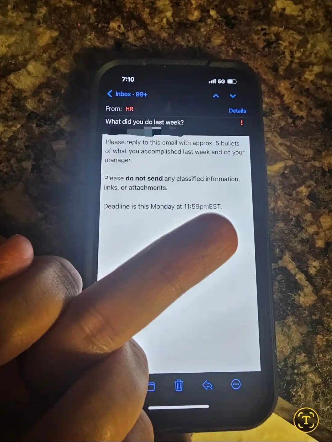 A close-up photo shows a person's finger pointing at a smartphone screen displaying an email from HR asking for a summary of…