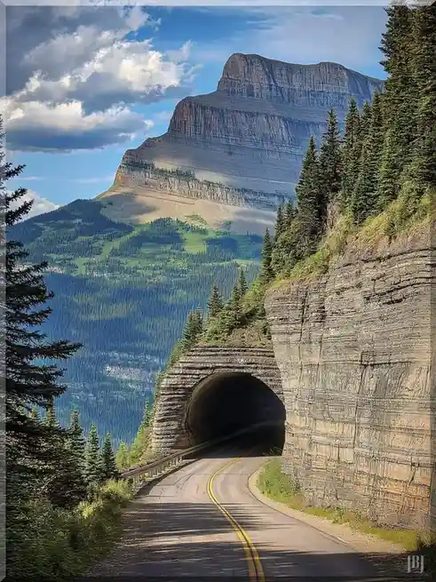 A scenic mountain road leads to a dark tunnel carved into a rocky cliffside, with a vast, layered mountain rising behind it…