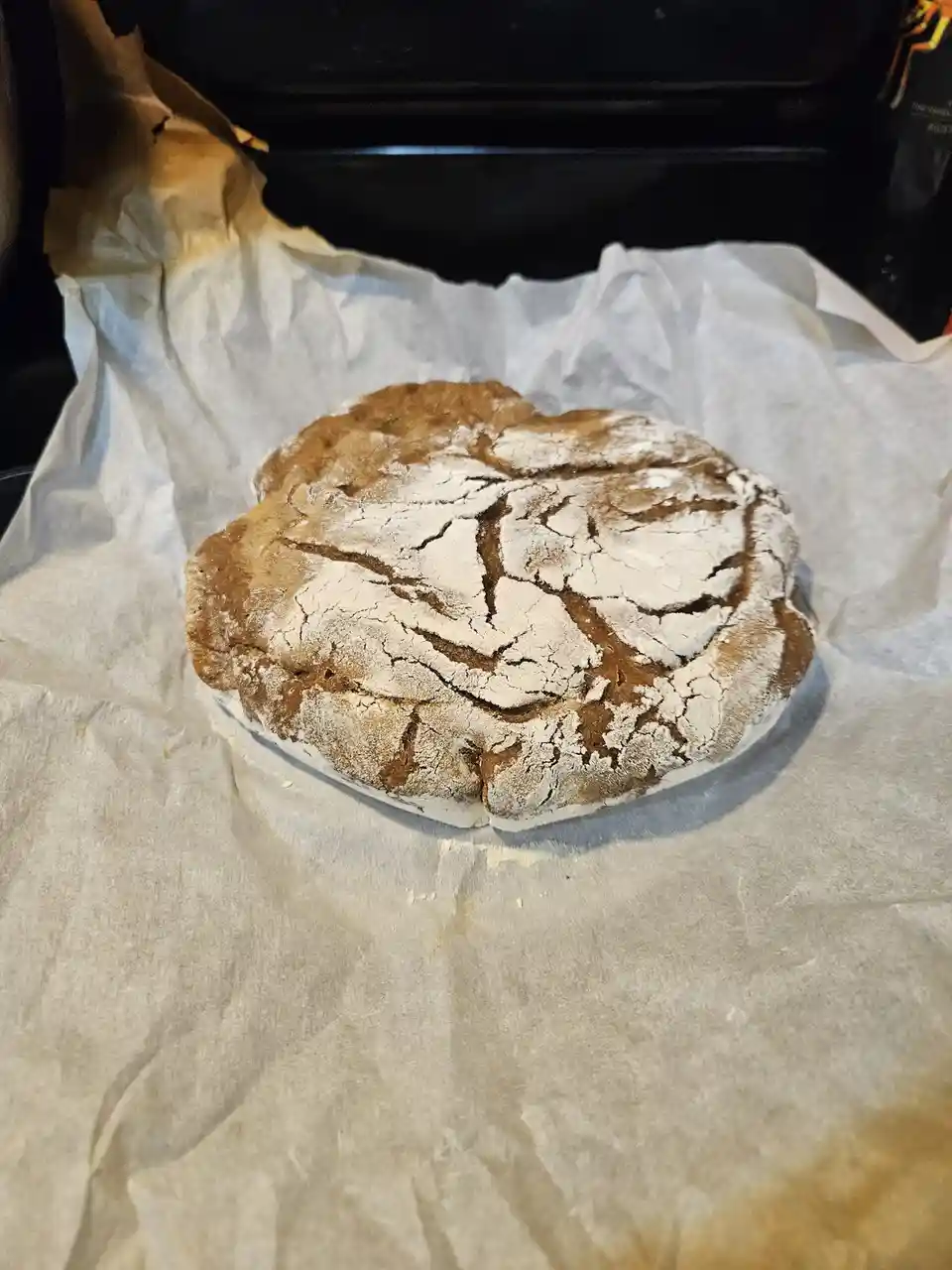 A round, rustic bread loaf with a cracked, flour-dusted crust sits on parchment paper. The overlaid text reads 'this is not…