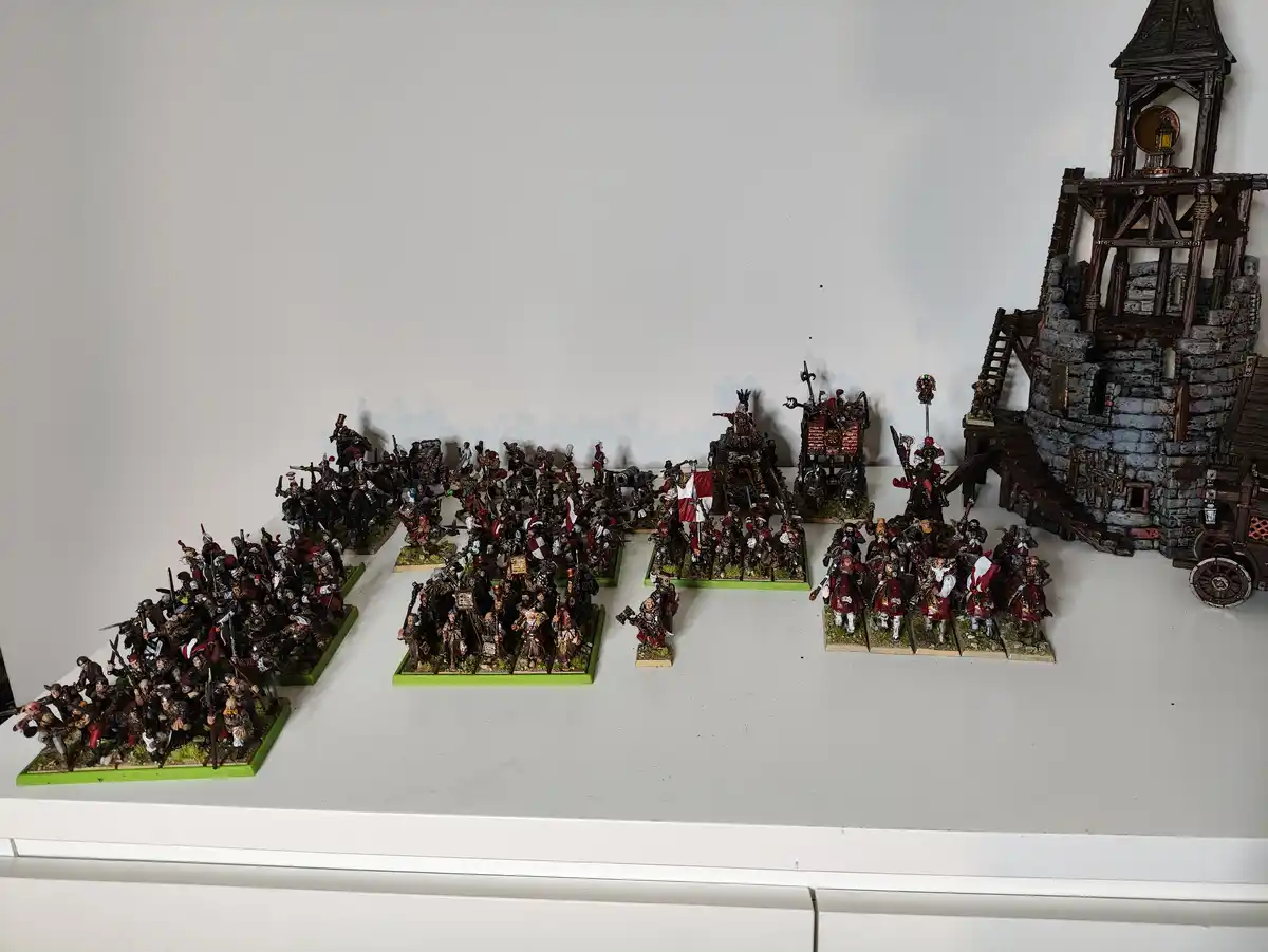 A large collection of painted fantasy miniatures, including infantry, cavalry, and monstrous figures, arranged on green…