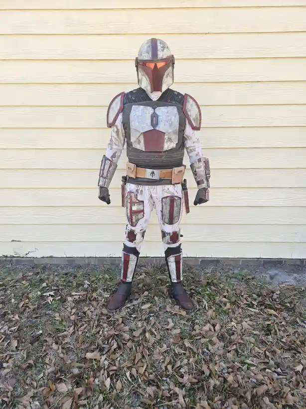 A person in a full, weathered Mandalorian armor costume stands facing away from the camera, showing the back of the helmet…