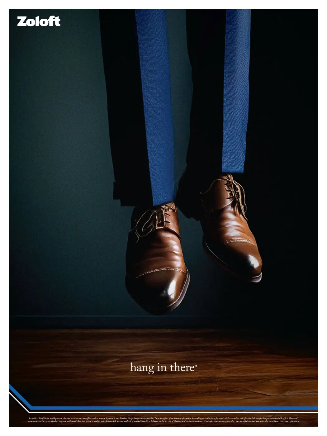 The image shows a person's legs and brown dress shoes hanging mid-air above a wooden floor, suggesting they are suspended or…