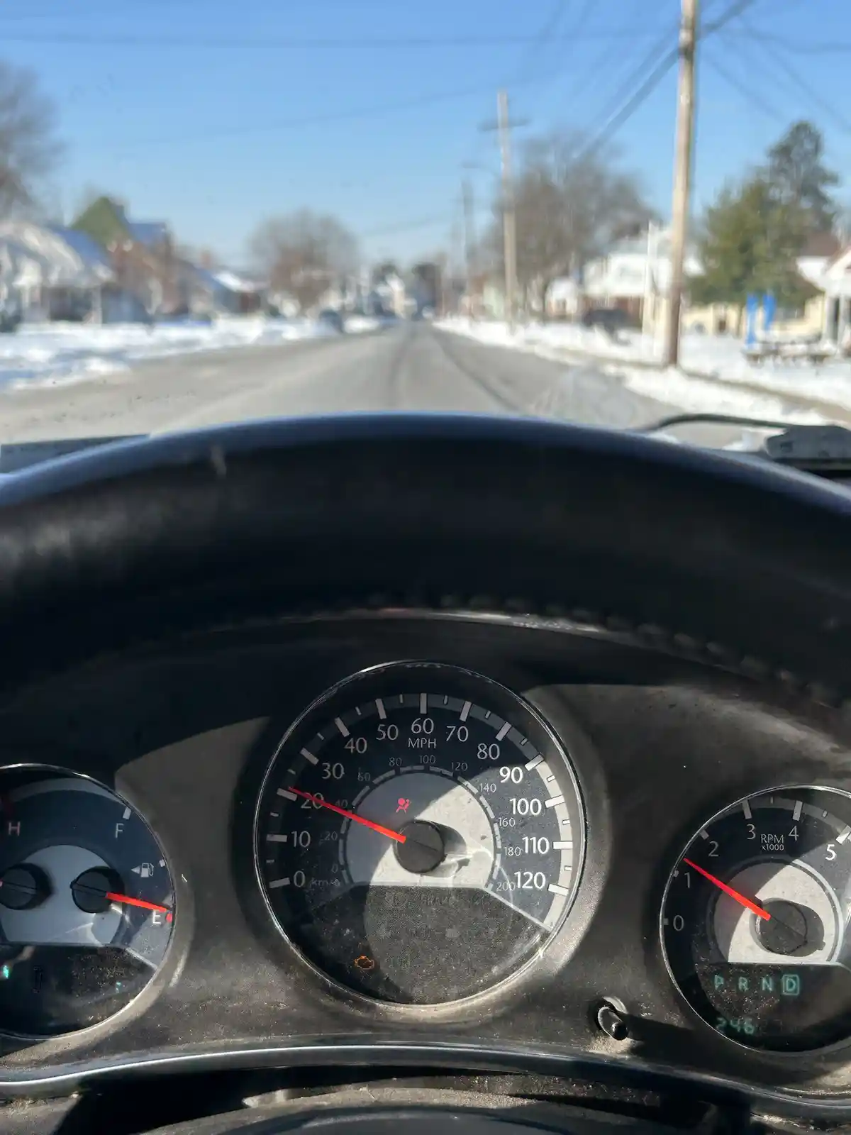 A close-up shot from inside a car shows the dashboard with the speedometer reading just under 20 mph, while the outside view…