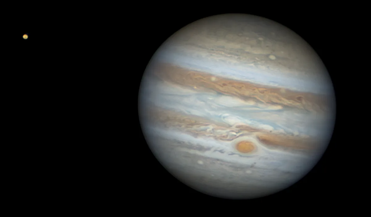 A space photograph shows the giant planet Jupiter with its prominent swirling bands and the Great Red Spot, while a much…