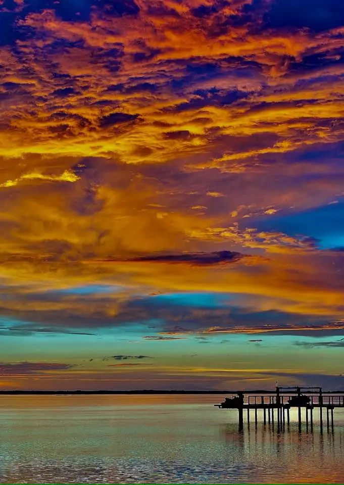 A vibrant sunset over water with a pier silhouette, overlaid with the text 'i'm not lazy, i'm in energy-saving mode'.