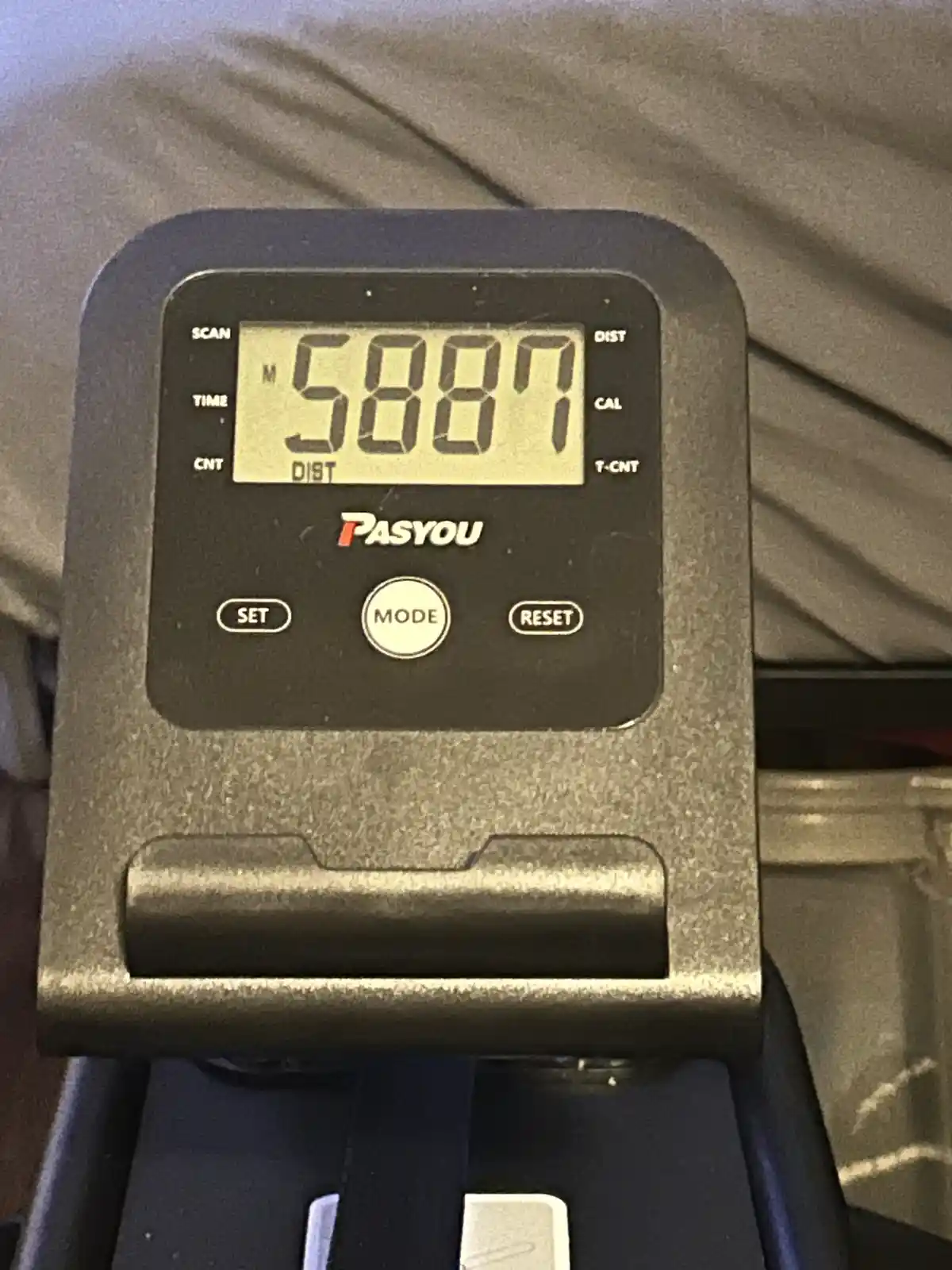 A close-up of a PASYOU brand treadmill console displaying the number 5887 in large digits, with buttons labeled SET, MODE…
