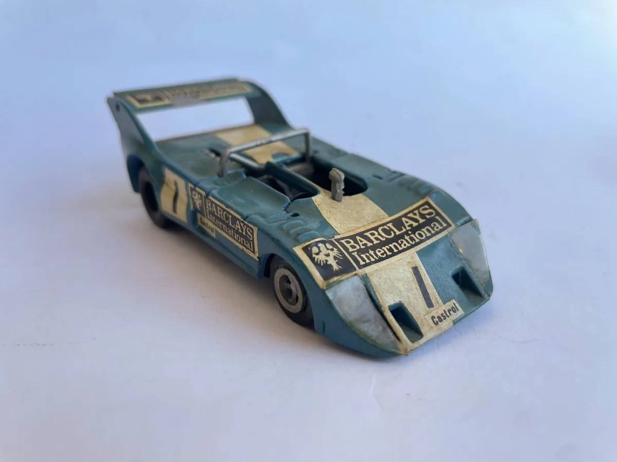A vintage green and beige toy race car, resembling a real racing vehicle with sponsor decals for 'BARCLAYS International'…
