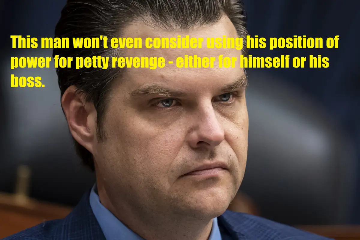 A close-up photo of a man with dark hair and a serious expression, wearing a blue suit and light blue shirt. Yellow text…