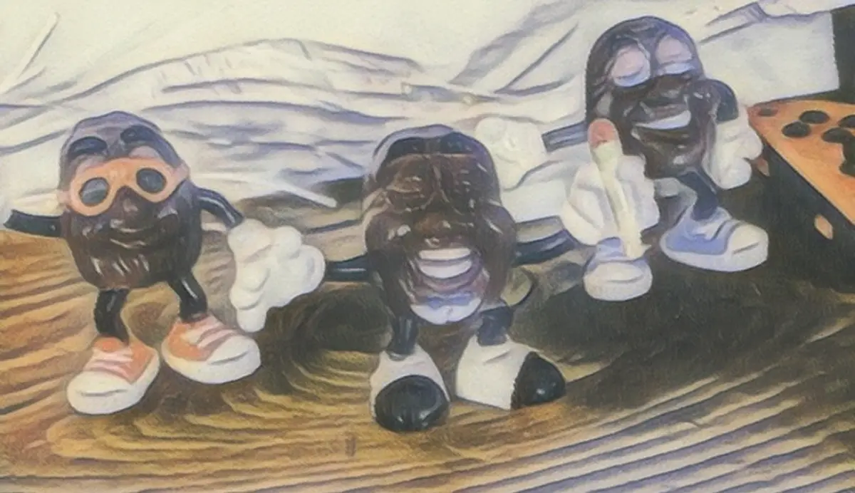 Three small, dark, cartoonish figures with exaggerated facial expressions stand on a wooden surface. The figure on the left…