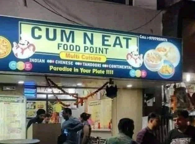 A blurry photo of a restaurant sign that reads 'CUM N EAT FOOD POINT' with 'Multi Cuisine' and lists Indian, Chinese…