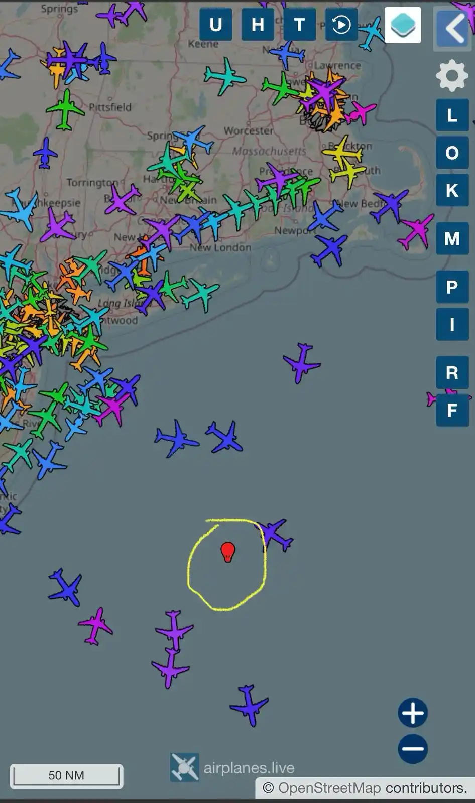 A screenshot of the airplanes.live website showing a map of New England with numerous colorful airplane icons densely…