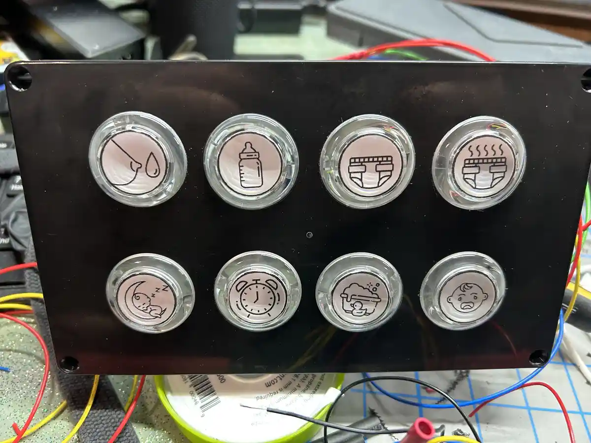 A custom-built electronic panel with eight round buttons, each featuring a simple line drawing icon: a droplet (possibly for…