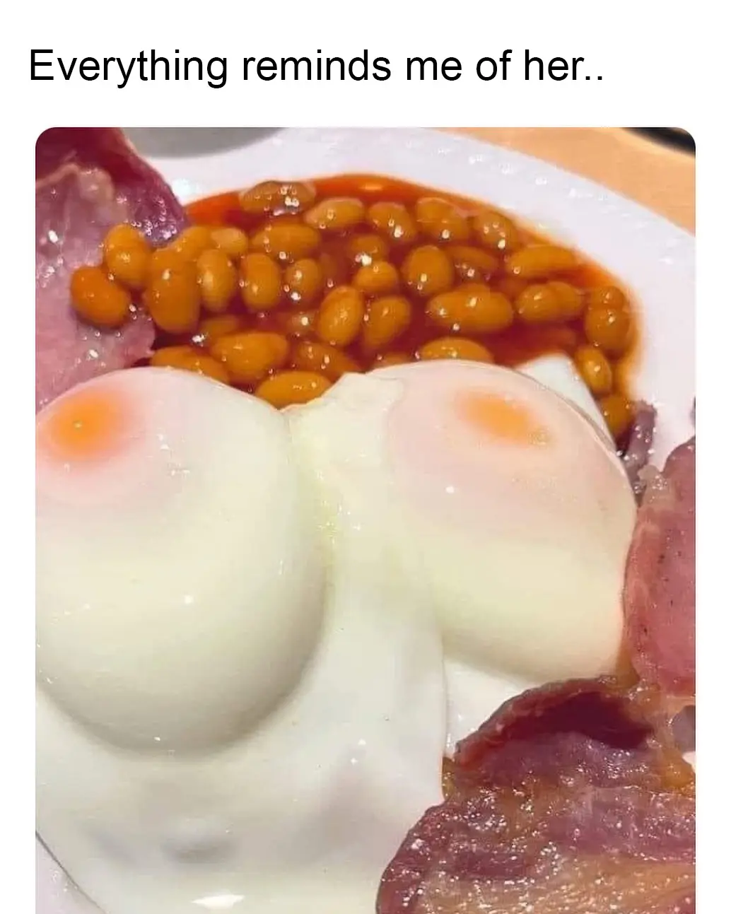 A close-up photo of a plate of breakfast food, featuring two poached eggs with yolks visible, a pile of baked beans in…