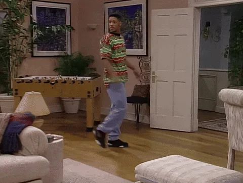 A still image from the TV show 'The Fresh Prince of Bel-Air' shows Will Smith walking across a living room in a striped…