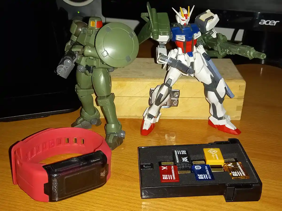 Two plastic robot action figures, one green with a shield and one white/blue/red with a rifle, stand on a wooden block. In…