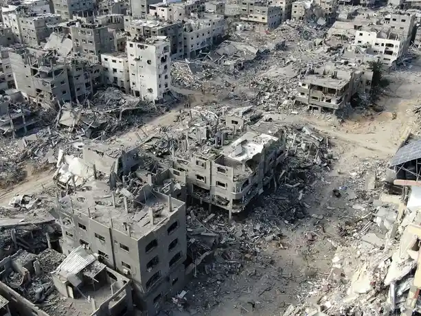 An aerial photograph shows a cityscape devastated by destruction, with numerous buildings reduced to rubble and debris…