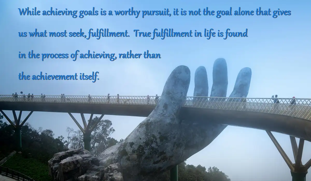 A large, weathered statue of a hand supports a bridge with people walking across it, set against a misty, forested landscape…