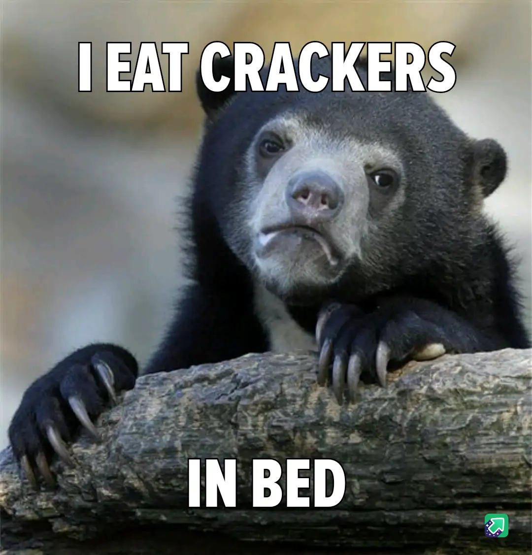 A close-up photo of a sloth bear resting its paws on a log, looking directly at the camera with a bored or unimpressed…