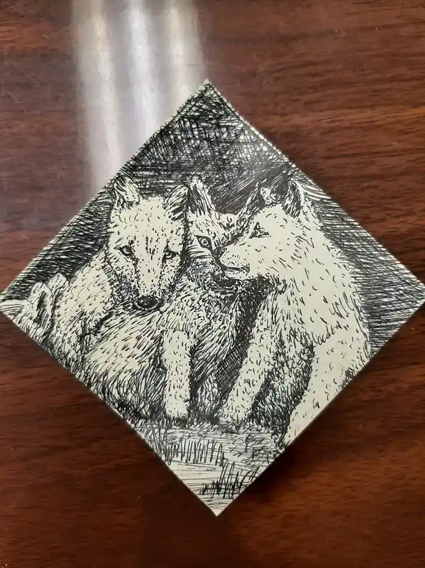 A black-and-white ink drawing on a diamond-shaped card depicts two foxes facing each other, one looking directly forward and…