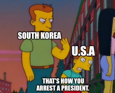 A still from The Simpsons shows a tall man labeled 'SOUTH KOREA' gesturing dismissively toward a shorter man labeled…