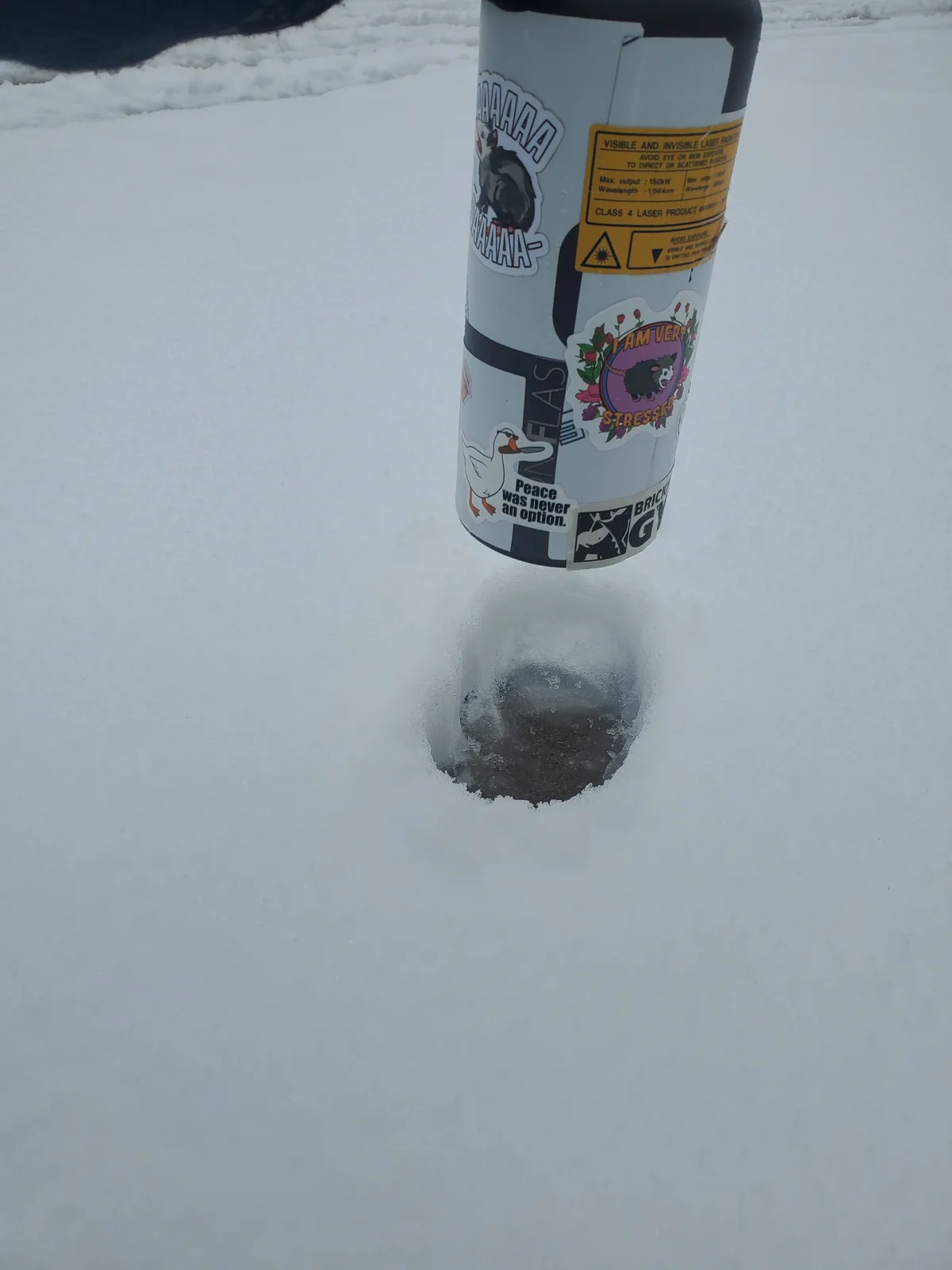 A silver thermos covered in various stickers, including one of a duck with the text 'Peace was never an option,' is stuck…