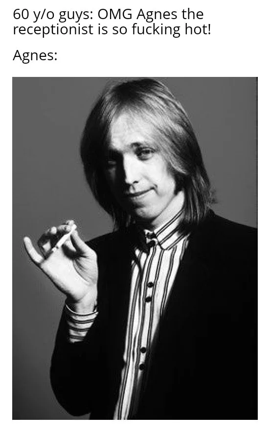 A black-and-white photo of a man with shoulder-length hair, wearing a striped shirt and dark jacket, holding a cigarette…