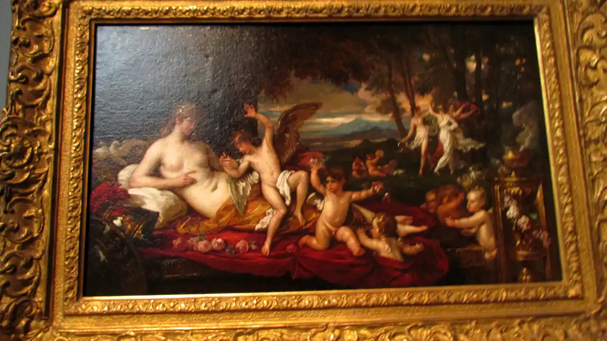 A classical painting in a gilded frame depicts a reclining nude woman surrounded by cherubs and mythological figures in a…