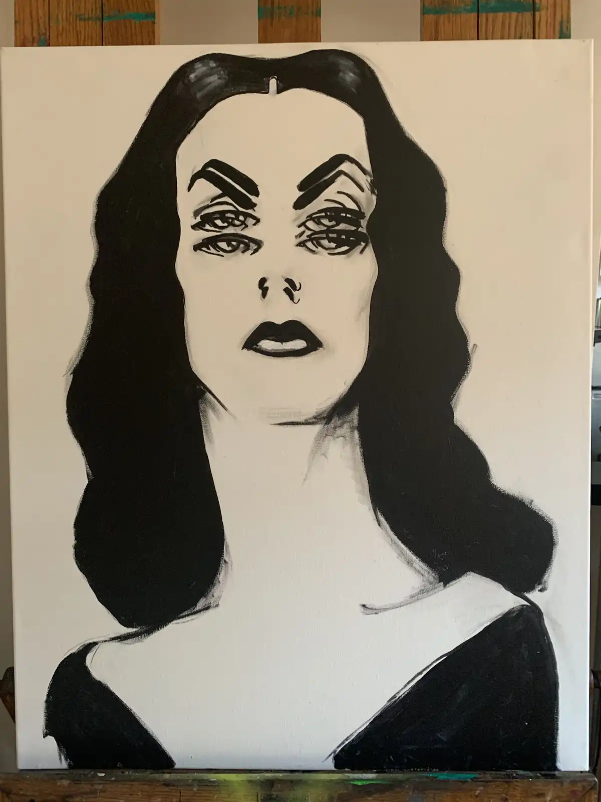 A black-and-white painted portrait of a woman with long dark hair, heavy eyeliner, and dark lipstick, resembling a classic…