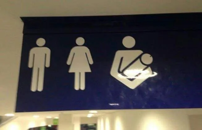 A blue restroom sign displays three white pictograms: a male figure, a female figure, and a parent holding a child. The sign…