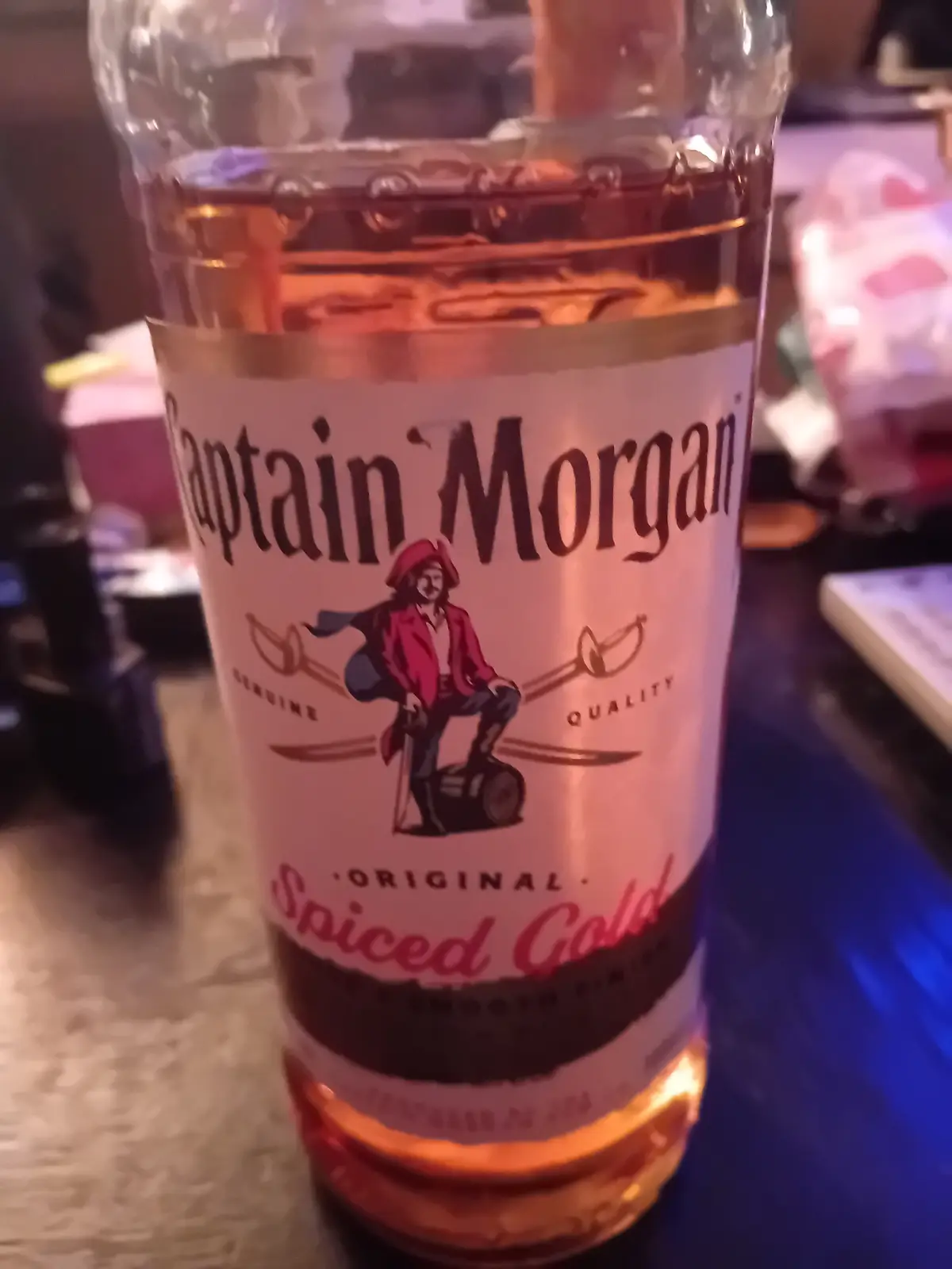 A close-up photo of a Captain Morgan Original Spiced Gold rum bottle, showing its label with the pirate logo and text…