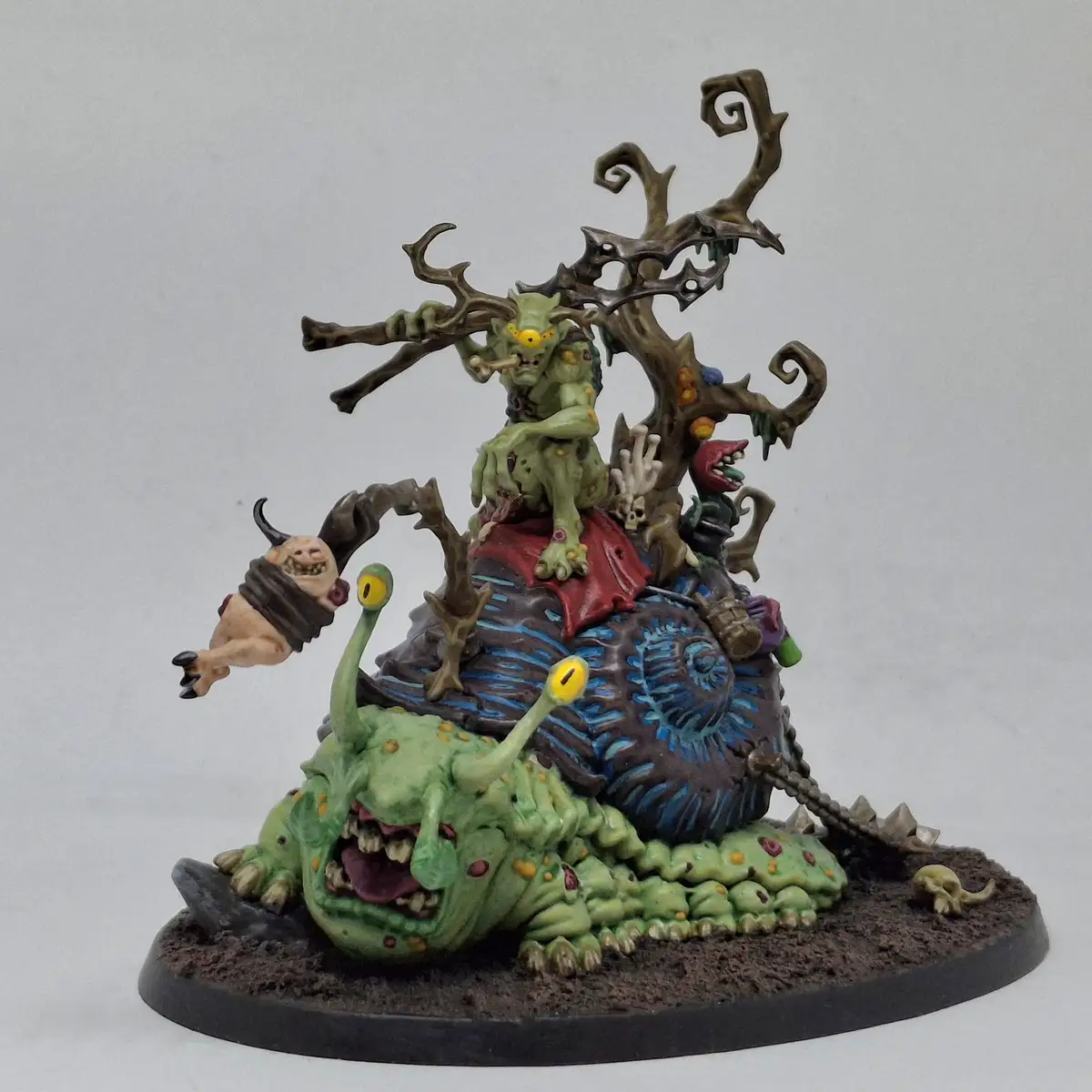 A highly detailed, painted miniature of a grotesque fantasy scene featuring a large green slug-like creature with two long…