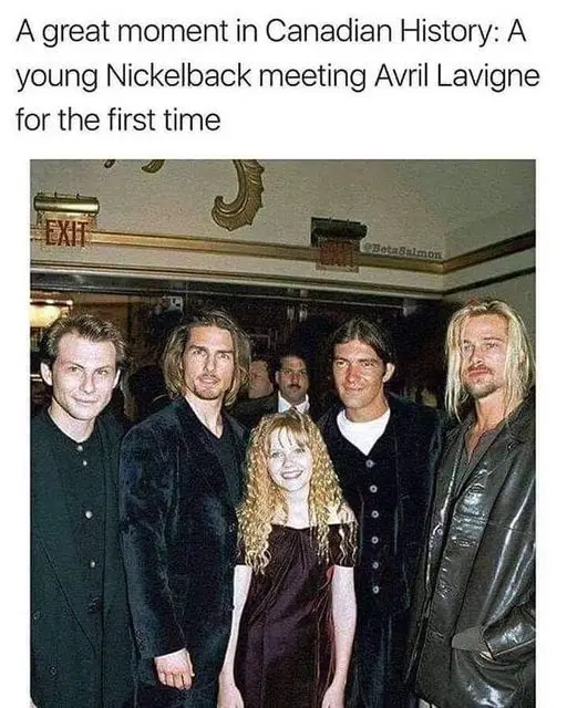 A group photo of five people, including four men in dark jackets and one young woman with curly blonde hair in a dark dress…