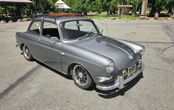 A silver vintage car with a roof rack parked in a lot, overlaid with the text 'i'm not a car, i'm a car with a roof rack'…