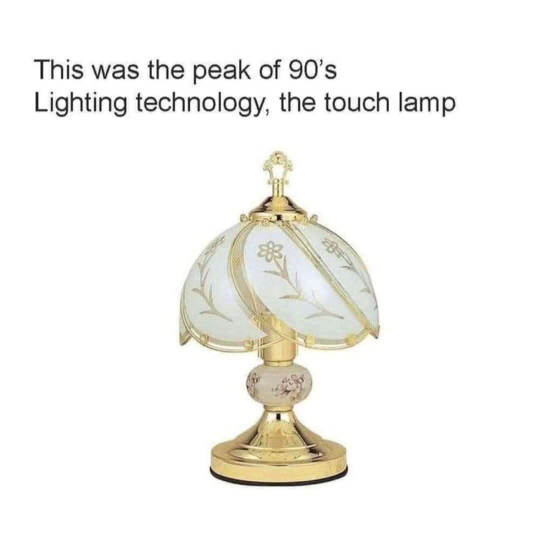 A decorative table lamp with a gold-colored base and ornate, frosted glass shade featuring floral etchings is shown against…