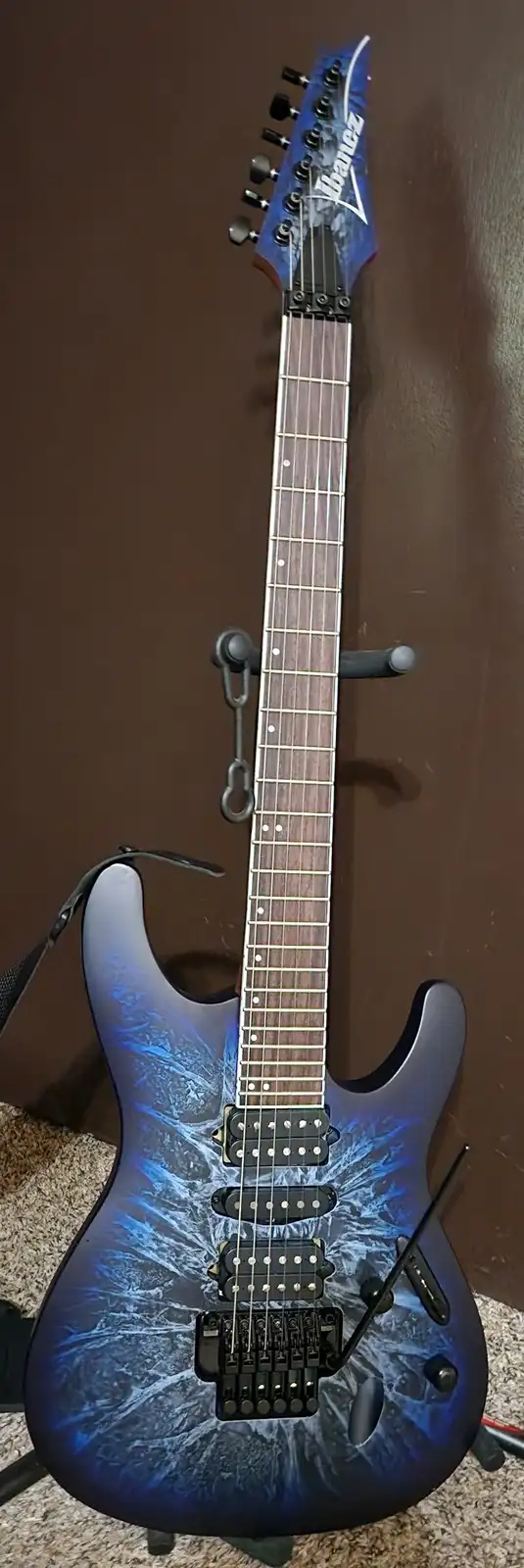 A blue and white marbled Ibanez electric guitar with a dark brown background, overlaid with the text 'i don't know what this…
