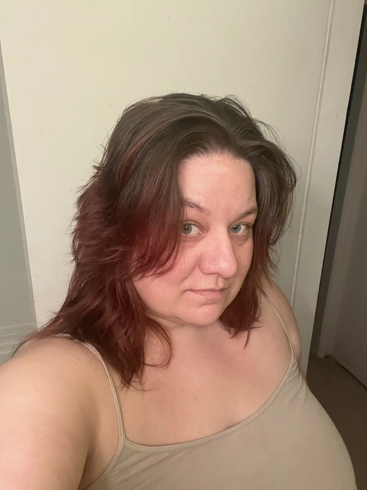 A selfie of a woman with shoulder-length hair that has a reddish-brown color on the lower half and darker brown on top…
