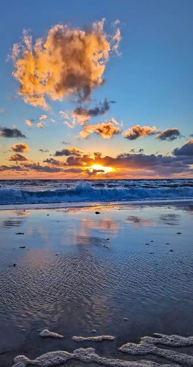 A serene beach sunset photo with golden clouds reflecting in wet sand, overlaid with the text 'i'm not crying, you're…