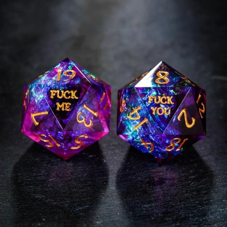 Two iridescent purple and blue 20-sided dice with gold numbers and text. The left die shows 'FUCK ME' on its visible face…