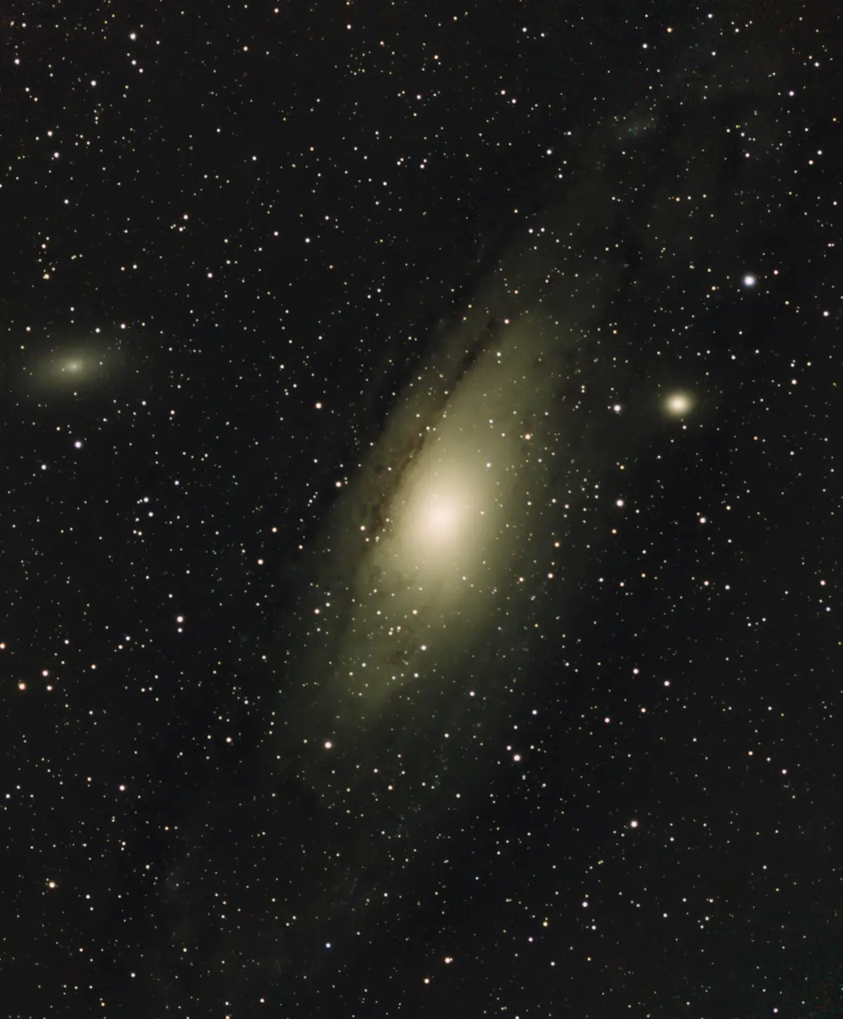 A deep-sky astrophotograph shows a spiral galaxy with a bright central bulge and faint spiral arms, set against a backdrop…