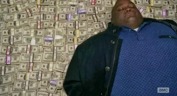 a man in a blue patterned shirt and dark jacket lies on his back atop a floor covered with stacks of US dollar bills, eyes…