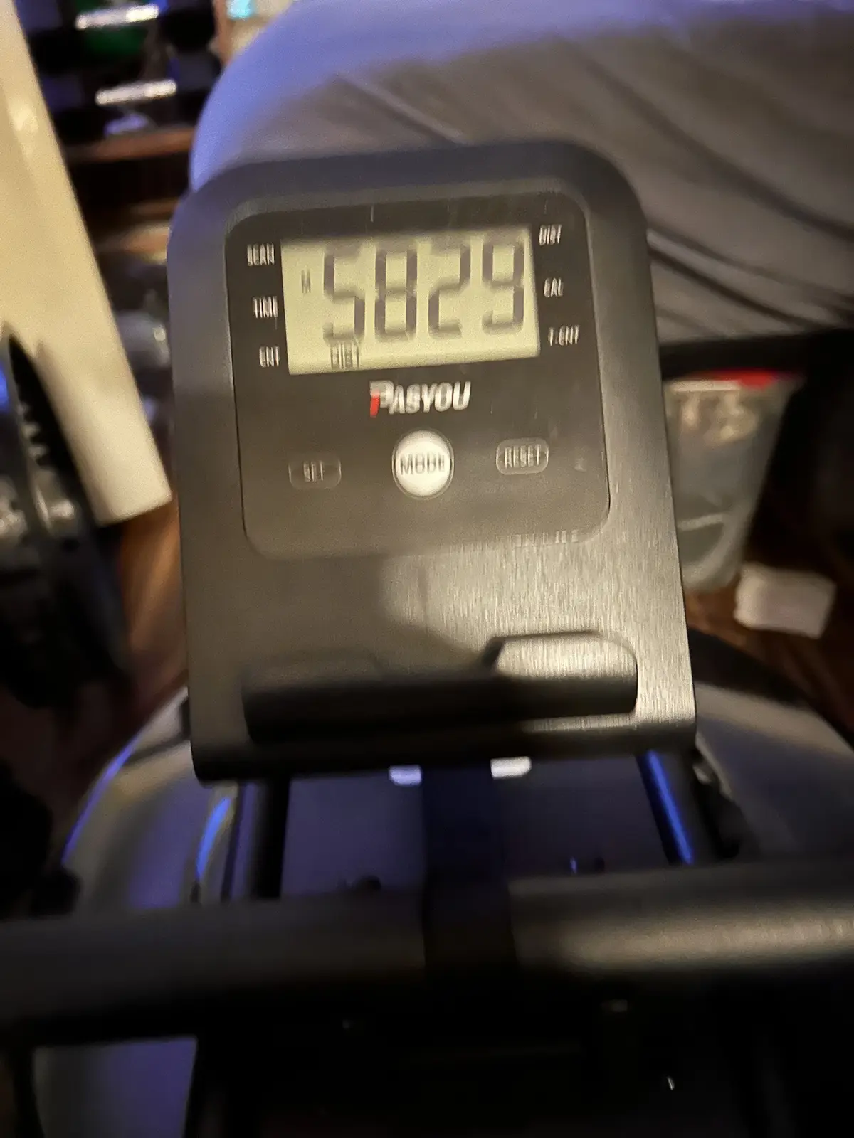 A close-up photo of a treadmill's digital display showing the number 5829, with the brand name 'PASYOU' visible below. The…