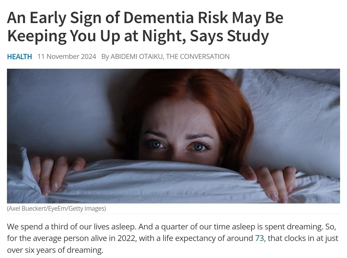 A woman with red hair lies in bed, peeking over a white pillow with wide, anxious eyes. The image is a screenshot of a news…