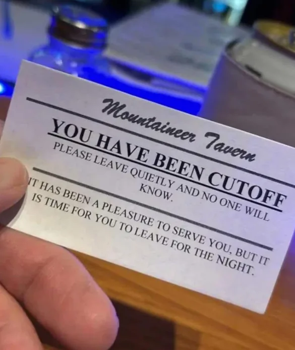 A hand holds a white card from 'Mountaineer Tavern' with bold text stating 'YOU HAVE BEEN CUTOFF' and polite instructions to…