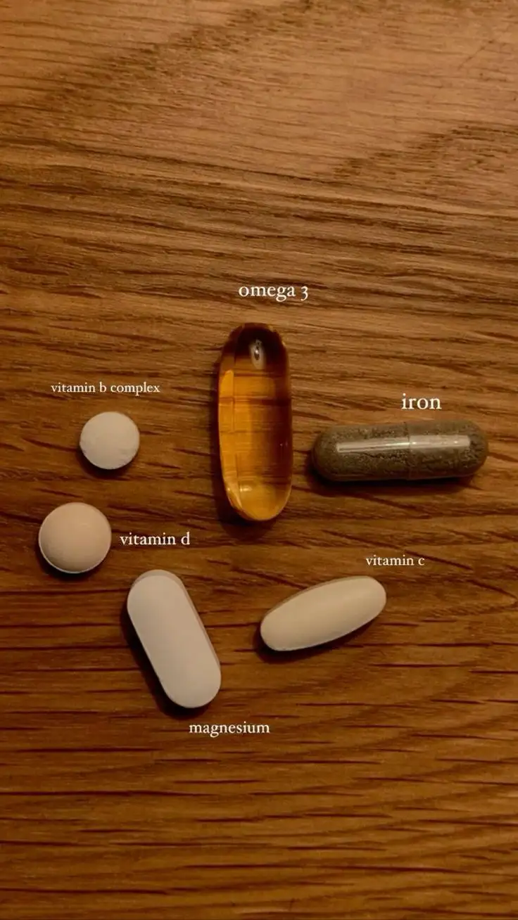 Several different supplement pills — labeled vitamin b complex, vitamin d, magnesium, omega 3, iron, and vitamin c — are…