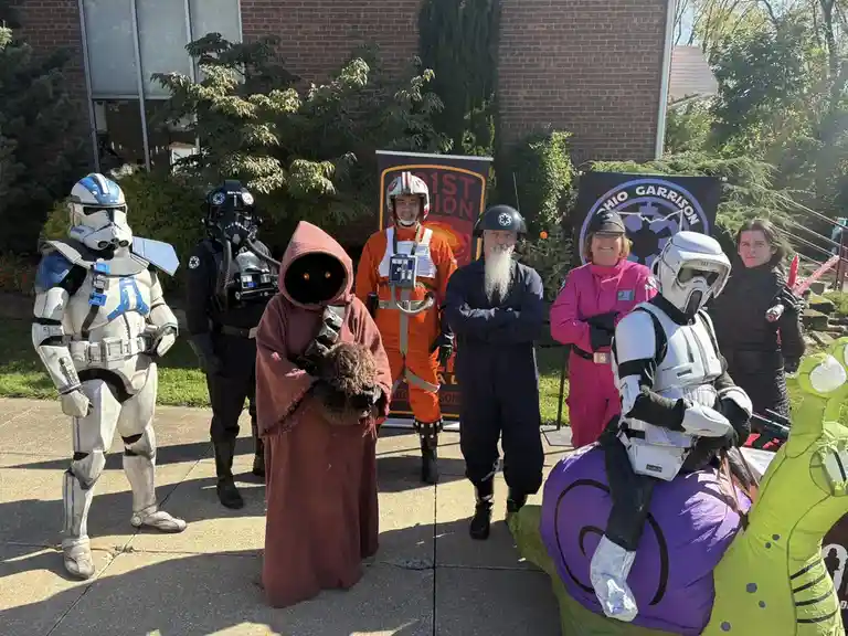 A group of people dressed as Star Wars characters, including a clone trooper, a stormtrooper, a jedi, a pilot, a man in a…