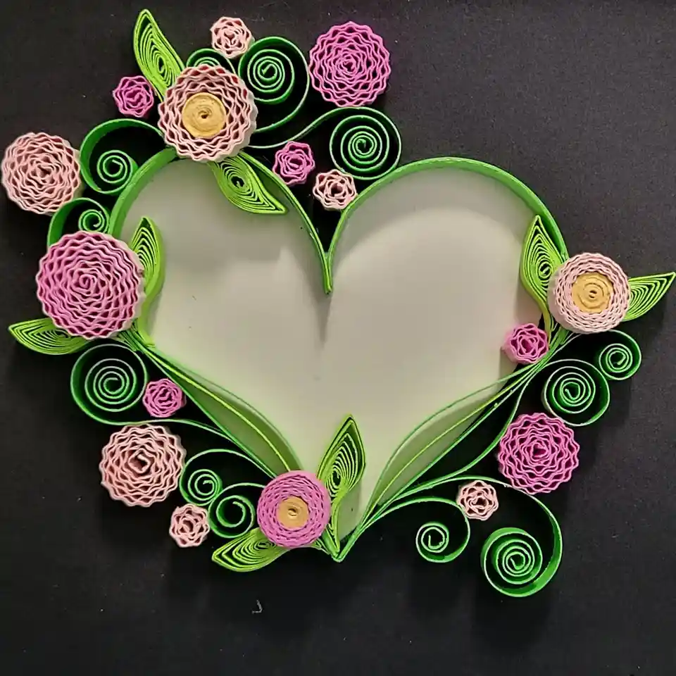 A handmade quilled paper art piece features a large, empty heart outline in light green, surrounded by decorative swirls and…