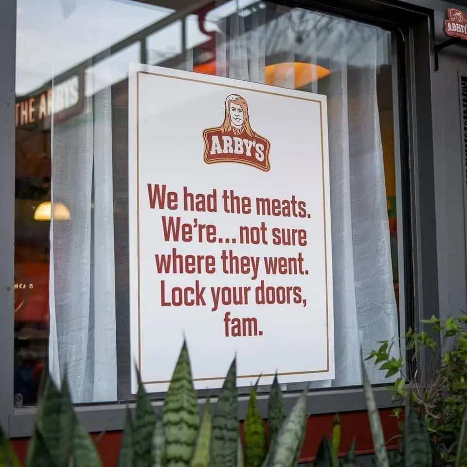 A sign posted on the window of an Arby's restaurant features the Arby's logo with a cartoon woman above the text. The sign…